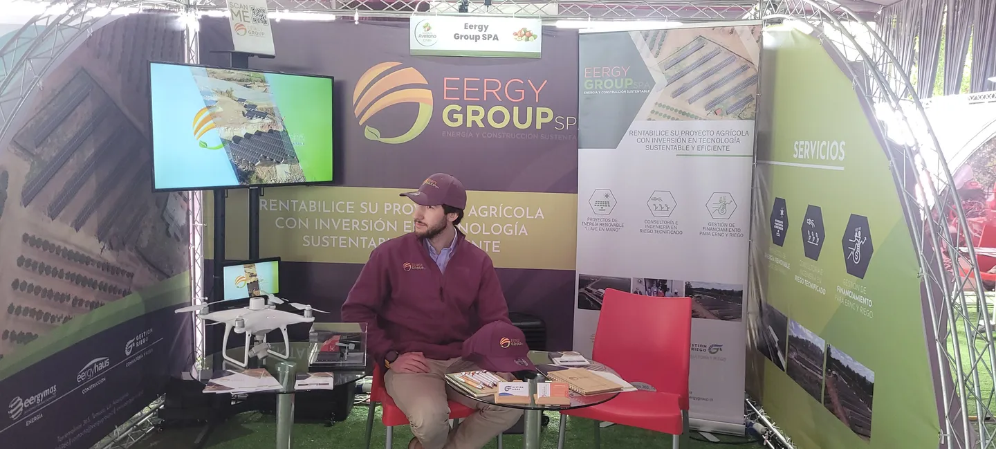 Stand con gráficas de EERGYGROUP, una mesa con material de exposición y una persona del equipo sentada.
